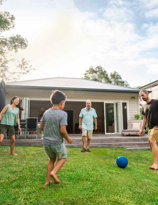 A family of four kick around a ball in the backyard.