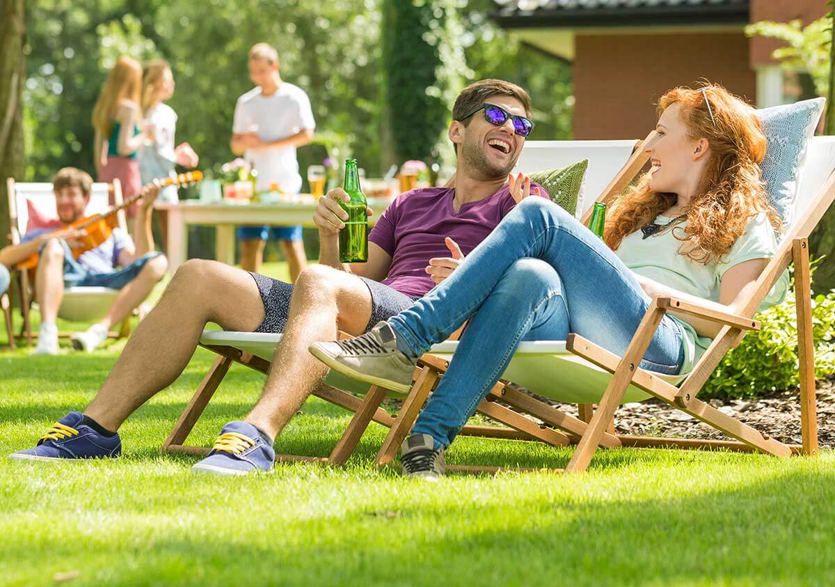 Summer Pests: Backyard celebration with family in background and couple sitting in lawn chairs in the front.