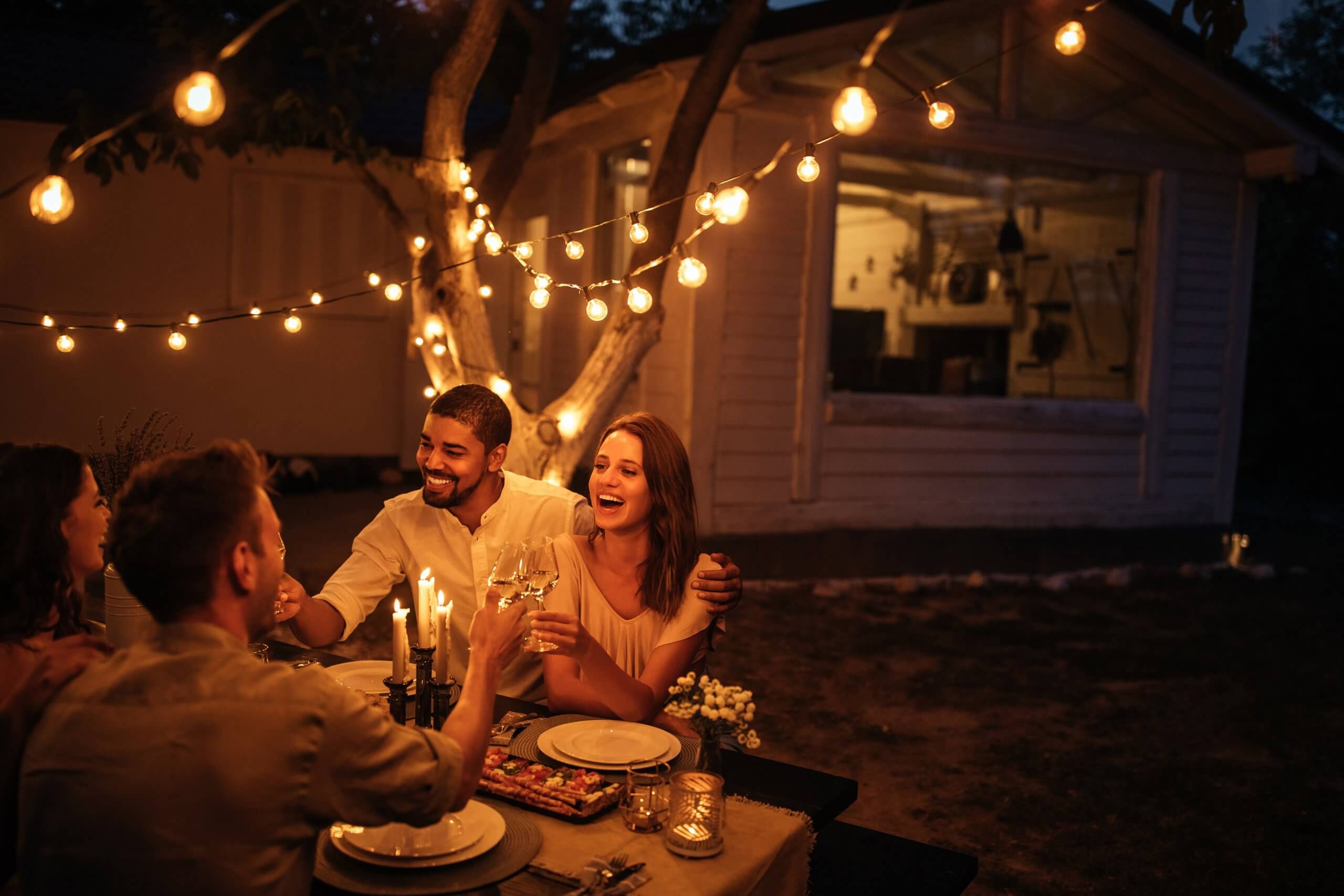 Adults celebrating at table in backyard, home behind them