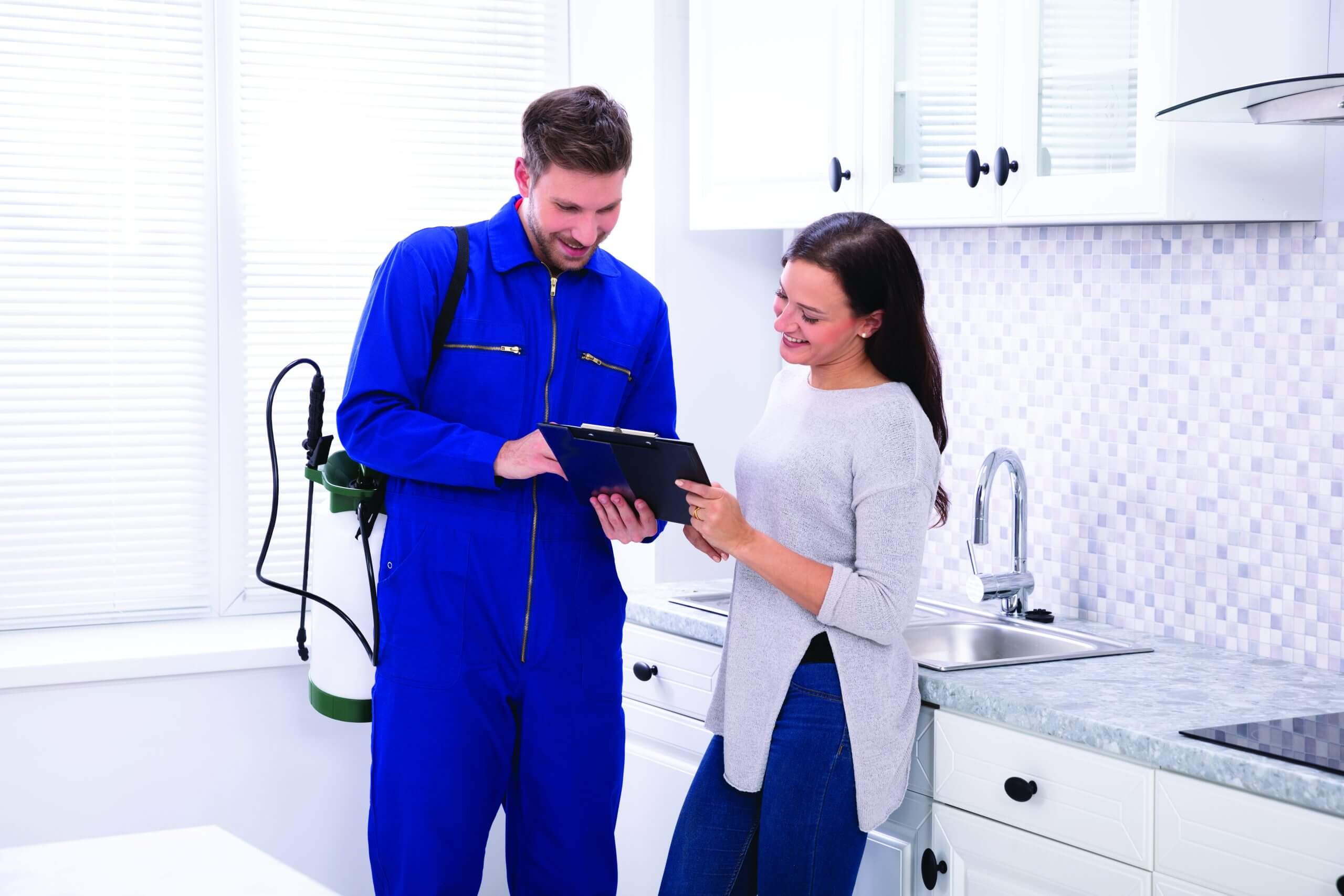 PMP with clipboard speaking to customer in kitchen, both are smiling